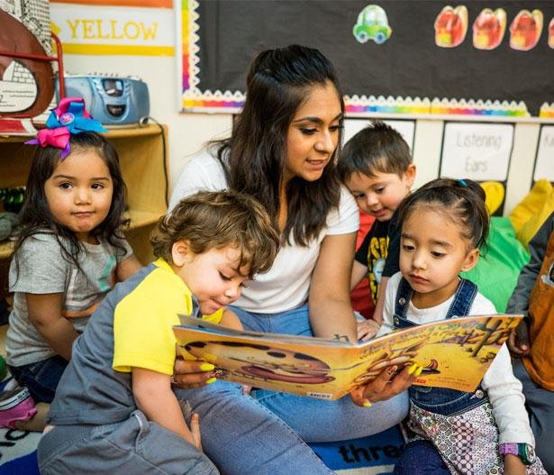 Preschool teacher reading a picture book to children