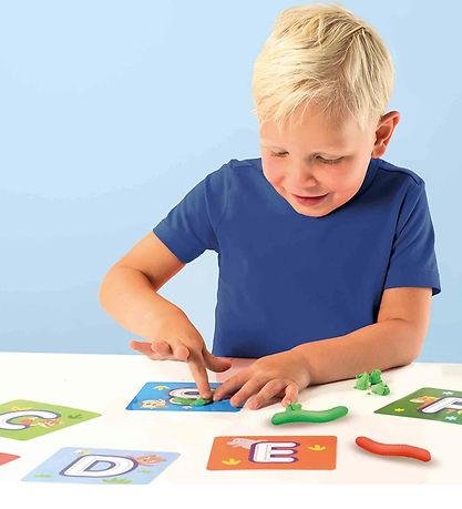 Preschool child making alphabet letters with clay
